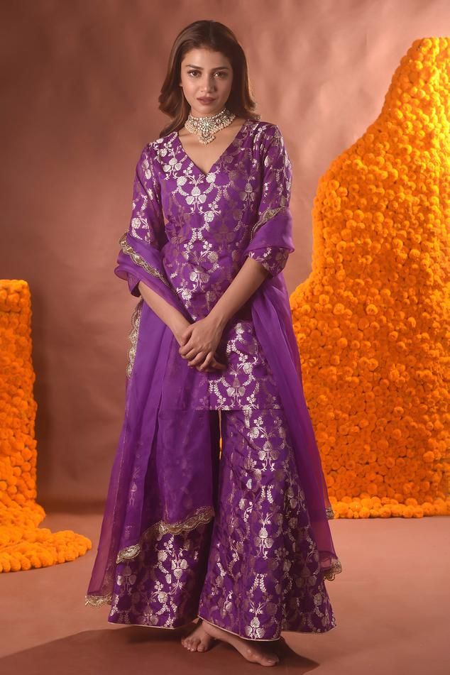 Purple banarasi silk kurta with floral pattern. Comes with sharara and a dupatta.
Components: 3
Type Of Work: Floral
Neckline: V Neck
Sleeve Type: Three quarter
Fabric: Banarasi silk
Color: Purple
Other Details: 
Note: Necklace worn by the model is not for sale.
Occasion: Mehendi and Haldi - Aza Fashions Unstitched Banarasi Silk Sharara With Dupatta, Semi-stitched Meenakari Sharara For Wedding, Tissue Silk Meenakari Dupatta For Eid, Traditional Purple Sharara For Festive Occasions, Purple Meenakari Traditional Wear For Eid, Traditional Drape Sharara In Banarasi Silk With Sheer Dupatta, Traditional Drape Sharara With Sheer Dupatta In Banarasi Silk, Unstitched Meenakari Tissue Silk Traditional Wear, Purple Banarasi Silk Sharara With Dupatta