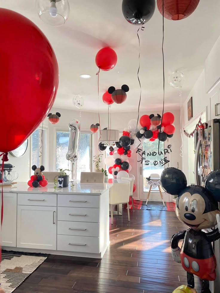 mickey mouse balloon decorations and balloons are hanging from the ceiling in this modern kitchen area