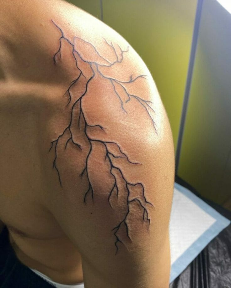 the back of a man's shoulder with a lightning tattoo on it