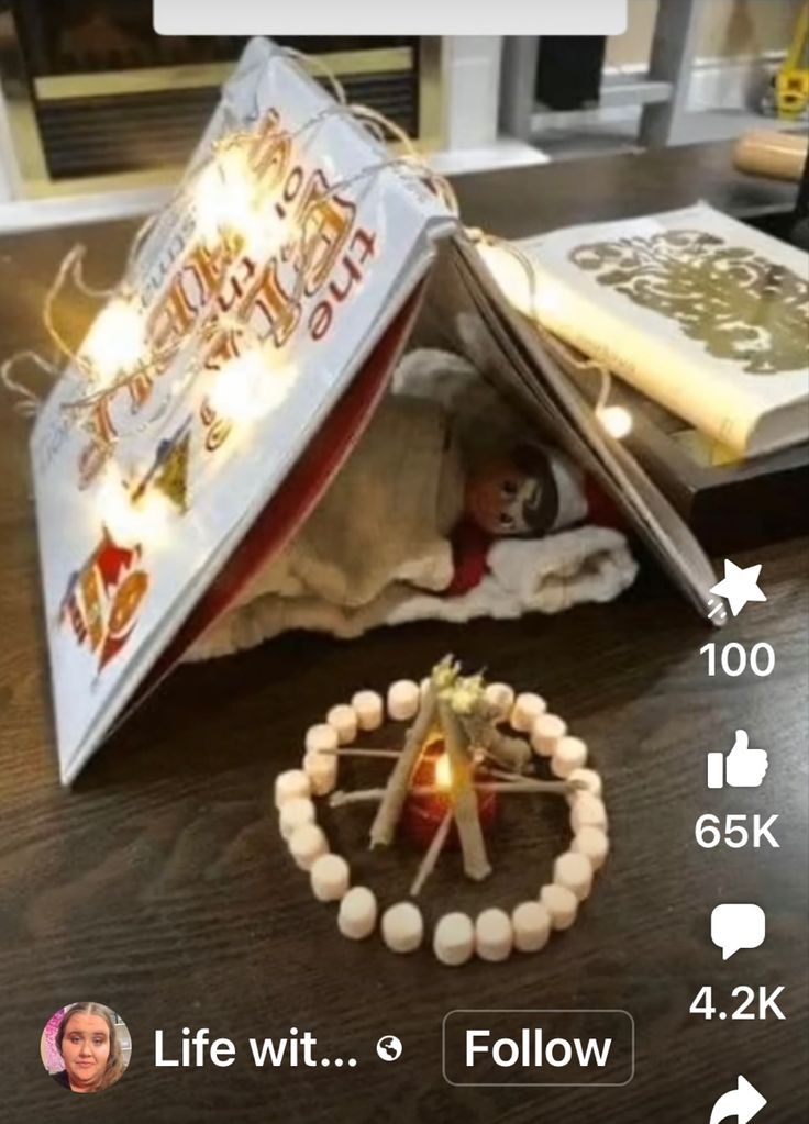 an open book on top of a wooden table next to a candle and some beads