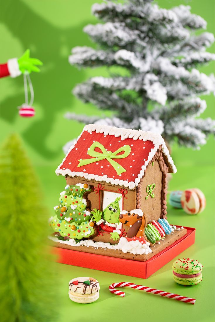 a gingerbread house decorated with christmas decorations and candy canes on a green background