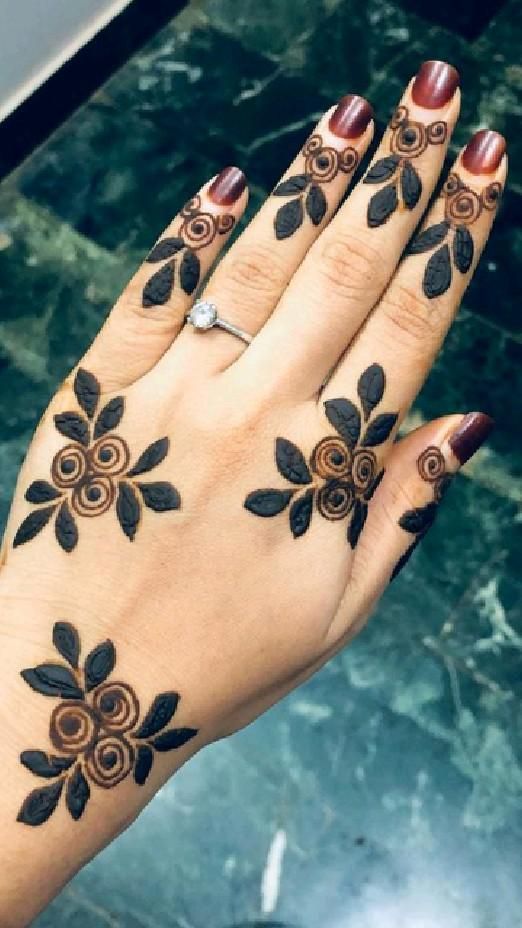 a woman's hand with black and brown tattoos on her palm, showing the design