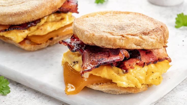 an egg and bacon breakfast sandwich on a white plate