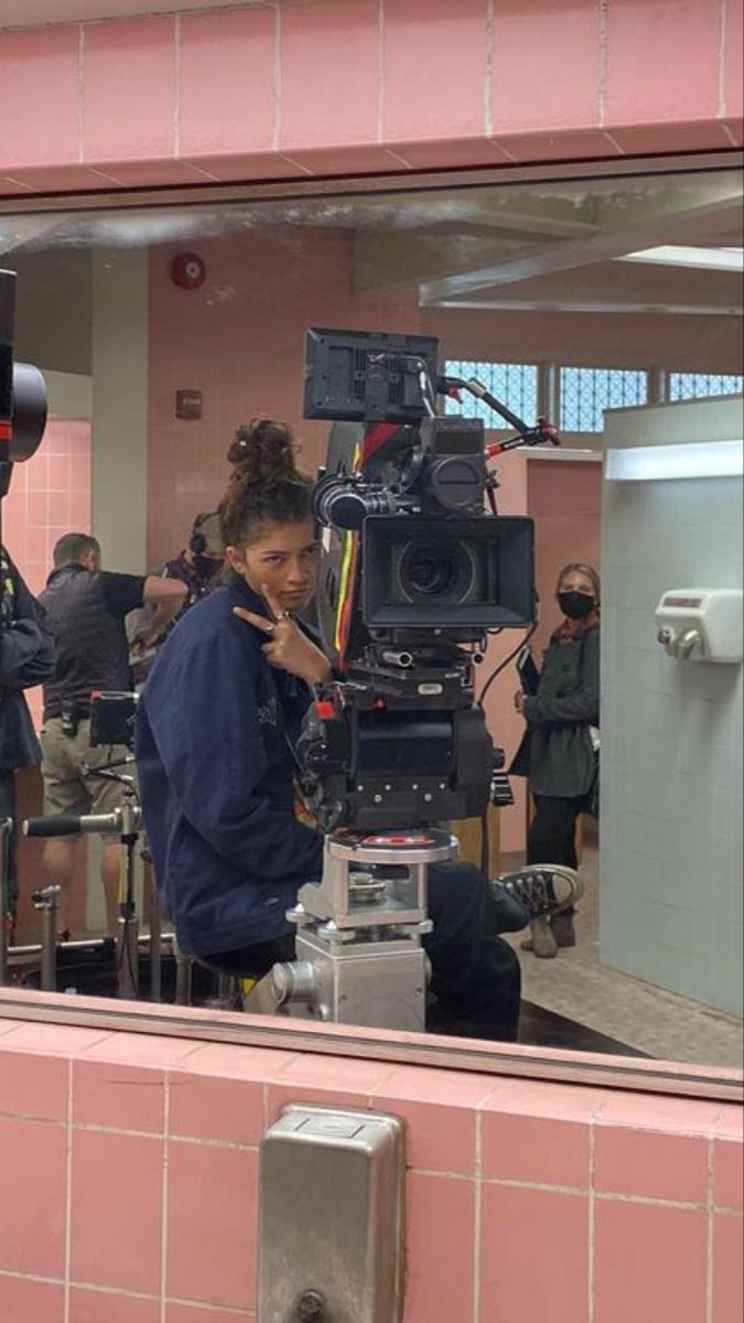 a man sitting in front of a mirror next to a camera