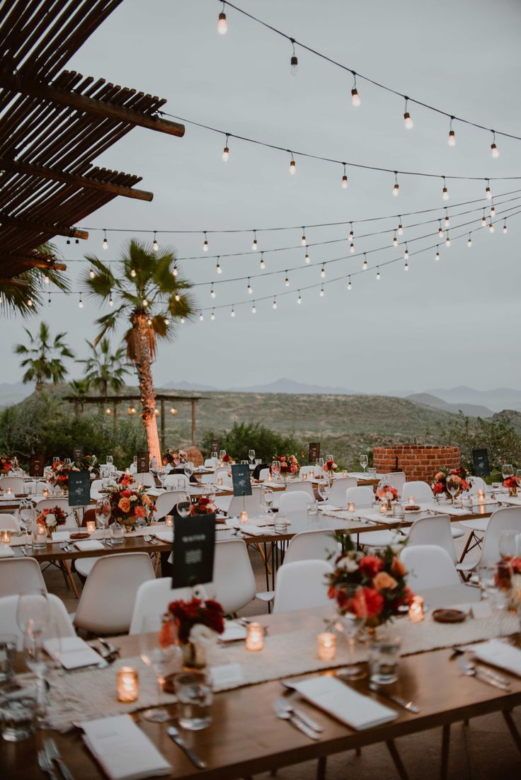 tables and chairs are set up for an outdoor event with string lights strung over them