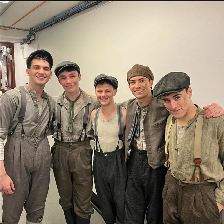 five boys in overalls and hats posing for a photo together, all smiling at the camera