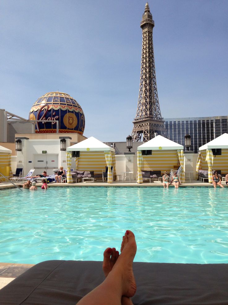 a person laying on their back in front of a pool with the eiffel tower in the background