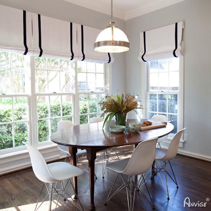 a dining room table with four chairs and a potted plant in the center is surrounded by windows