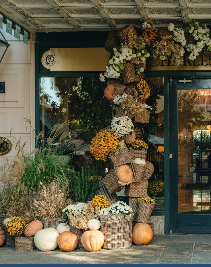 a store front with pumpkins and flowers on display