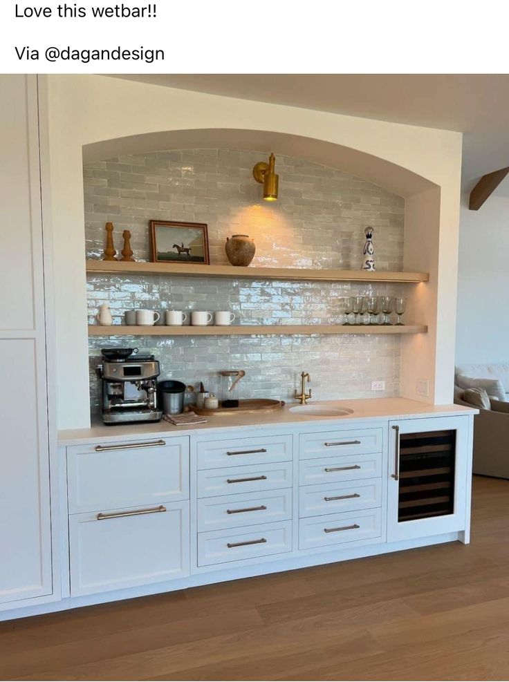 a kitchen with white cabinets and open shelving on the wall above it is shown