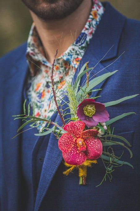 a man wearing a blue suit and flower boutonniere with red flowers on his lapel