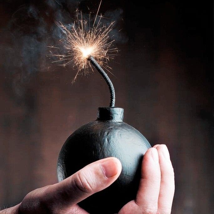 a hand holding a black ball with a sparkler in it