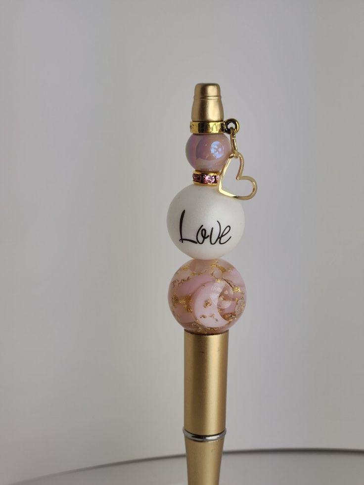 three glass beads with the word love on them sitting on top of a metal pole