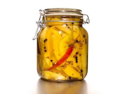 a glass jar filled with sliced bananas on top of a white table next to a red pepper