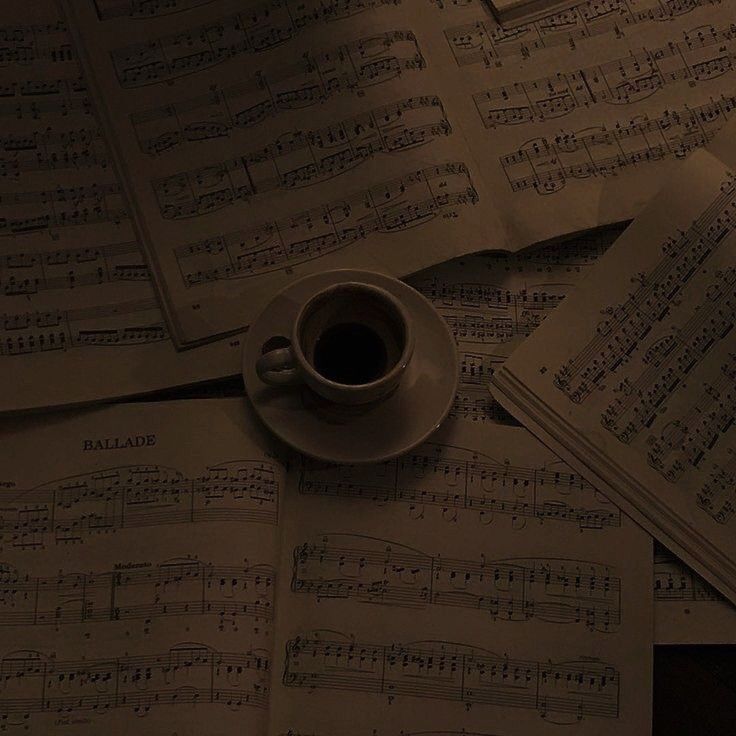 a cup of coffee sitting on top of sheet music