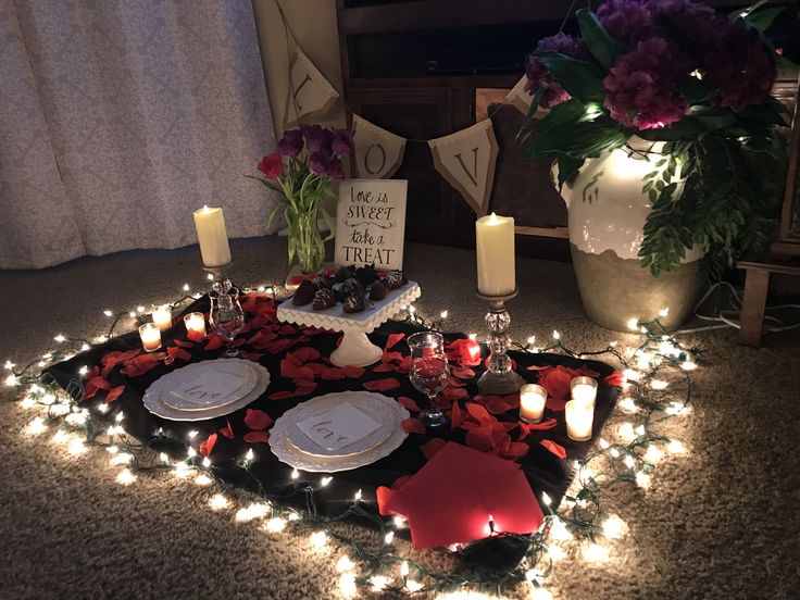 a table topped with plates and candles on top of a rug covered in red flowers