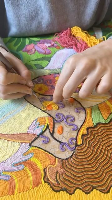 a woman is working on an intricately designed piece of art with scissors and thread