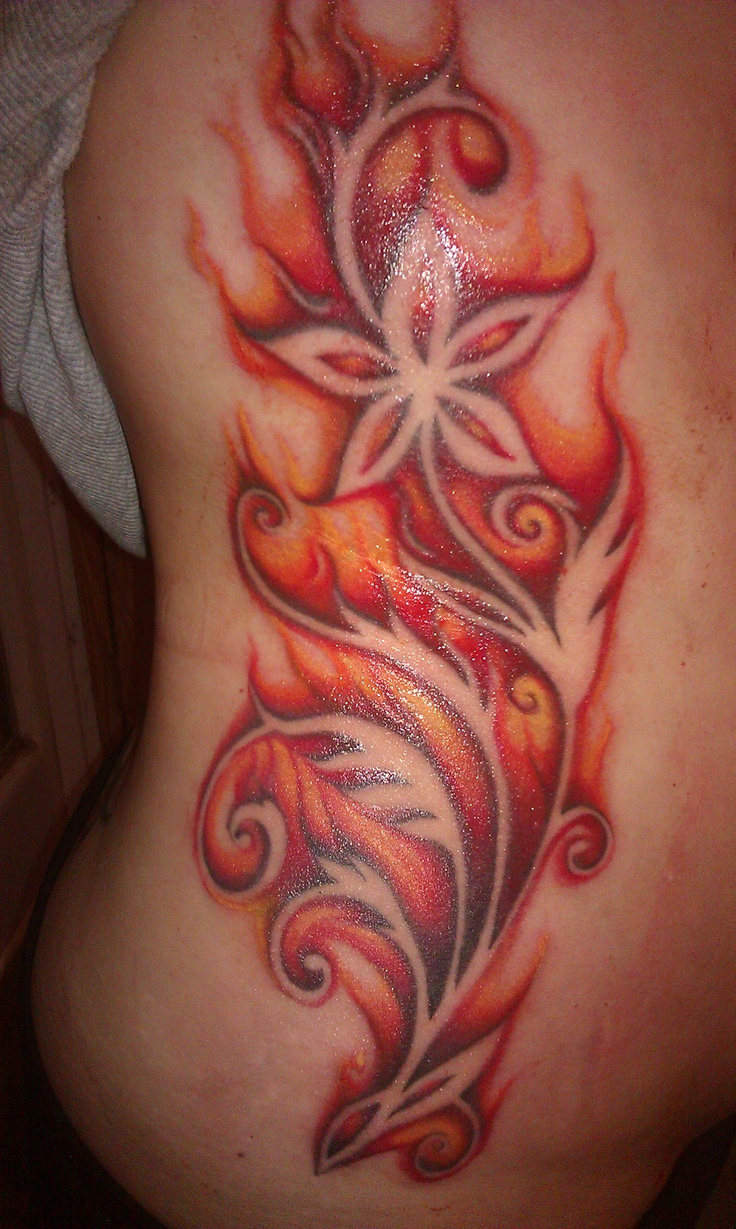 a woman's stomach with an artistic tattoo design on the side, and flames coming out of it