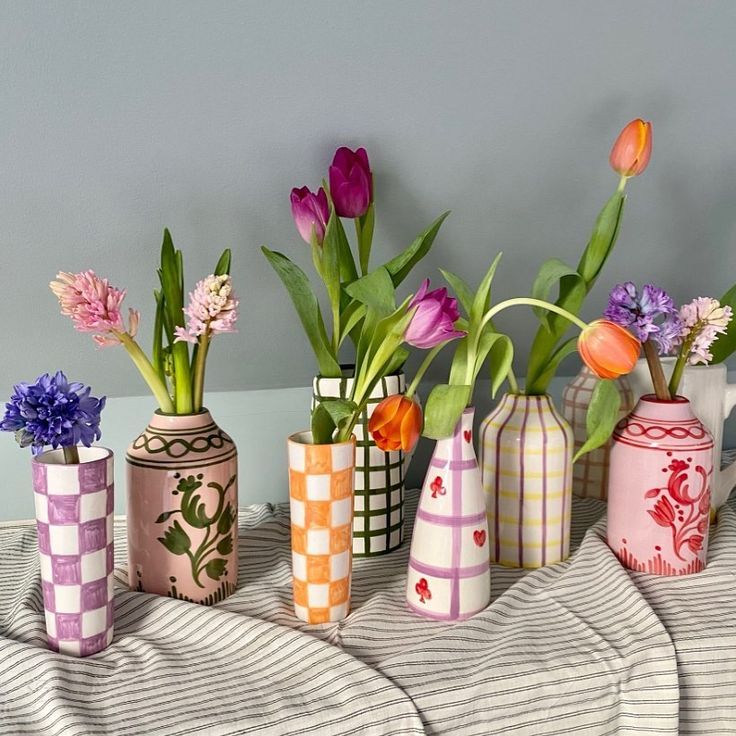 there are many vases with flowers in them on the bed side table or shelf