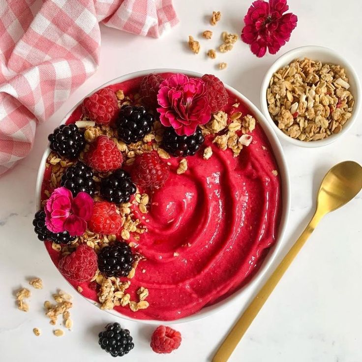 a bowl of yogurt with berries and granola on top next to a spoon