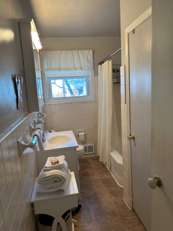 a bathroom with a sink, toilet and bathtub next to a shower curtained window