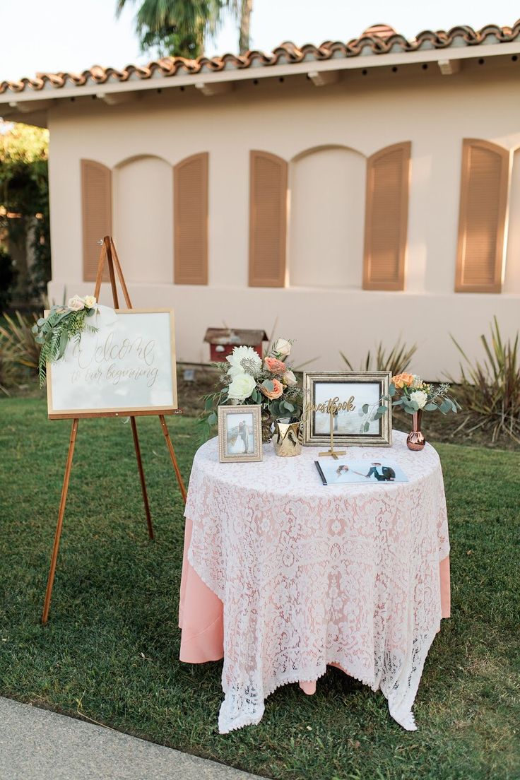 a table with pictures and flowers on it in front of a house for a wedding