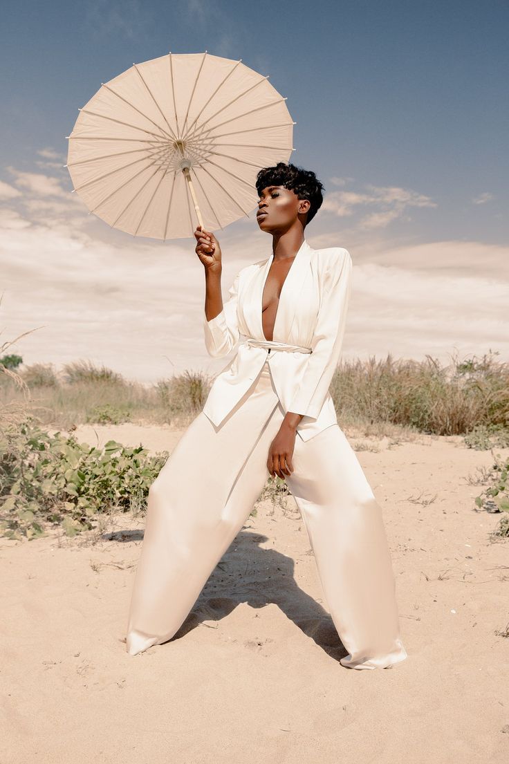 a woman in white is holding an umbrella over her head and posing for the camera