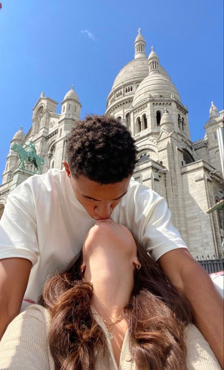 a man and woman kissing in front of a castle