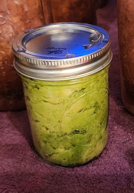 a jar filled with green liquid sitting on top of a purple blanket next to two large jars