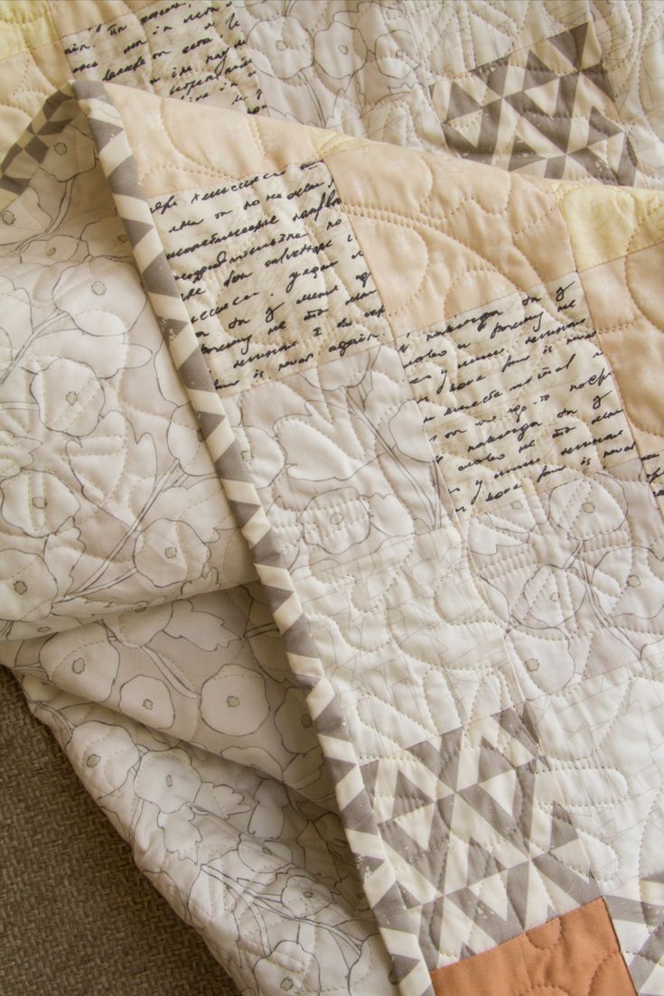 two quilts laying next to each other on top of a bed sheet with writing on them