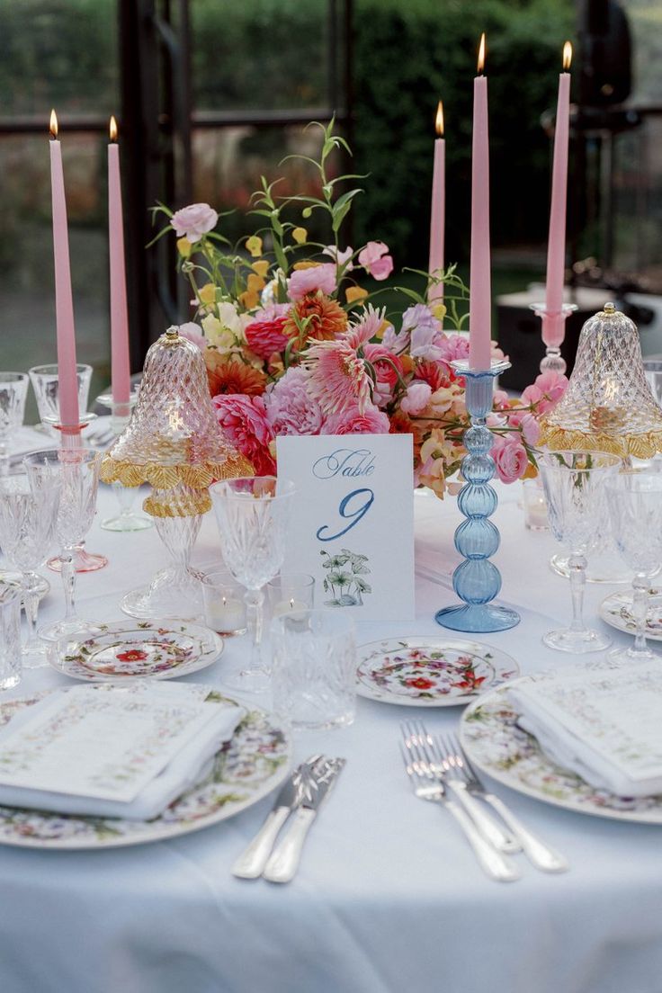 the table is set with pink flowers and candles