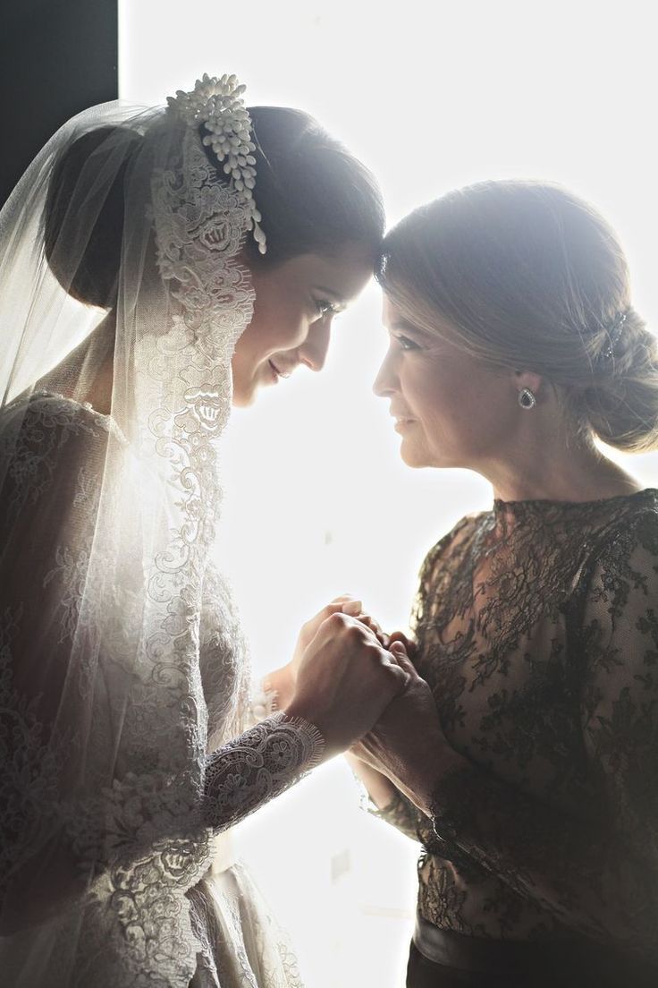 two women in wedding gowns standing next to each other and looking at each other