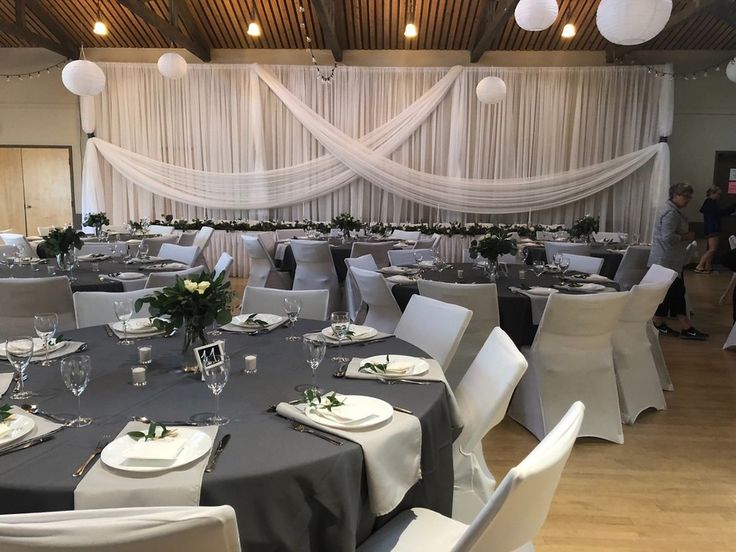 the tables are set up for an event with white and gray linens on them