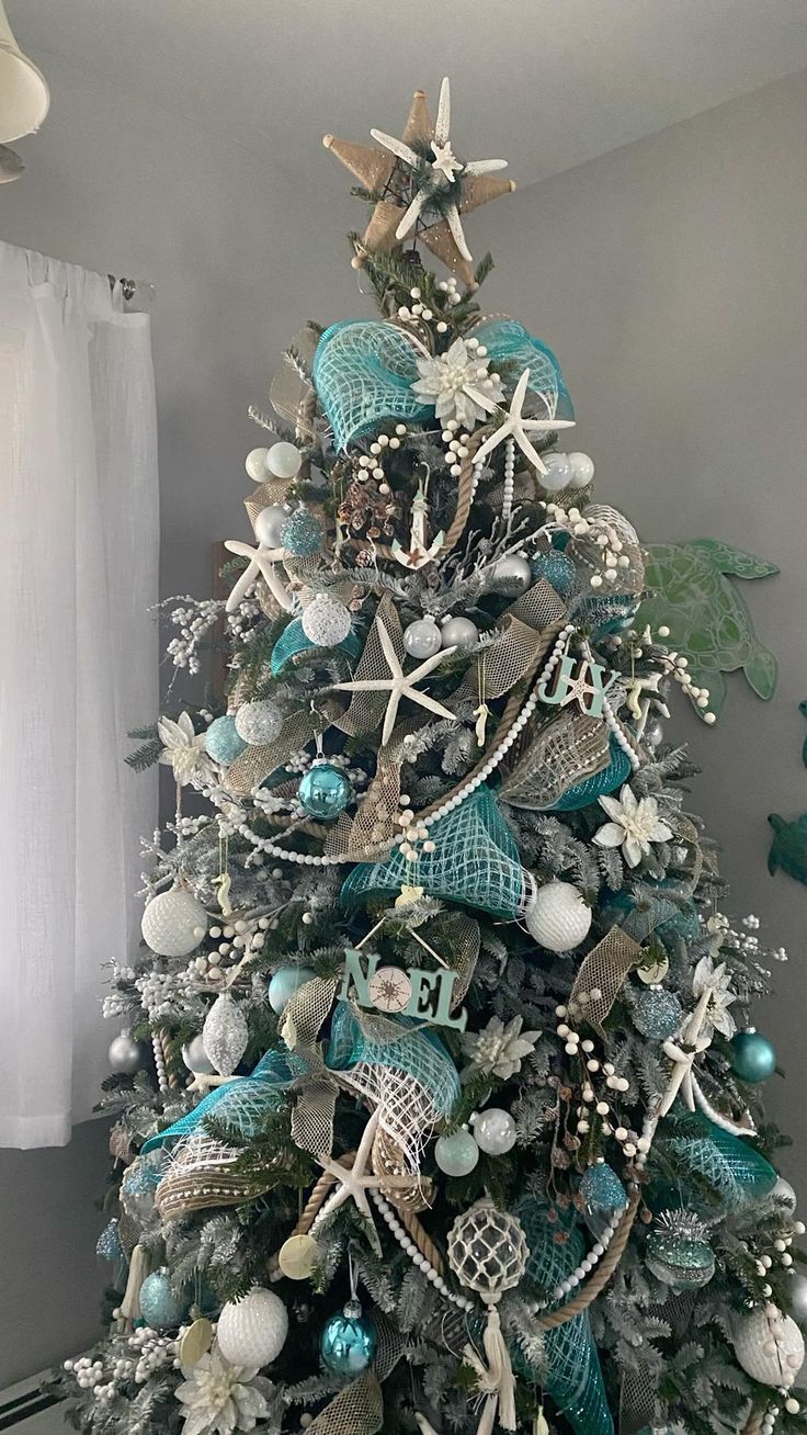 a christmas tree decorated with blue and silver ornaments, seashells and starfish