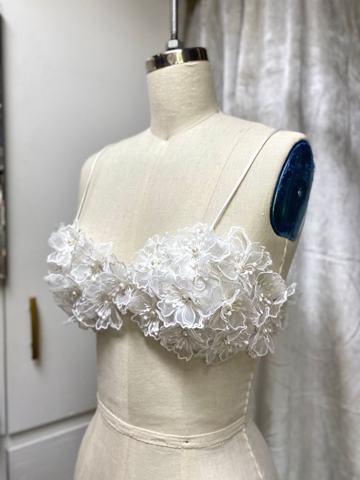 a mannequin with white flowers on it next to a dressmaker's dummy