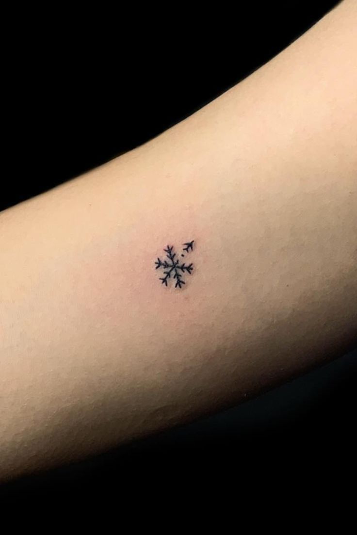 a small snowflake tattoo on the arm