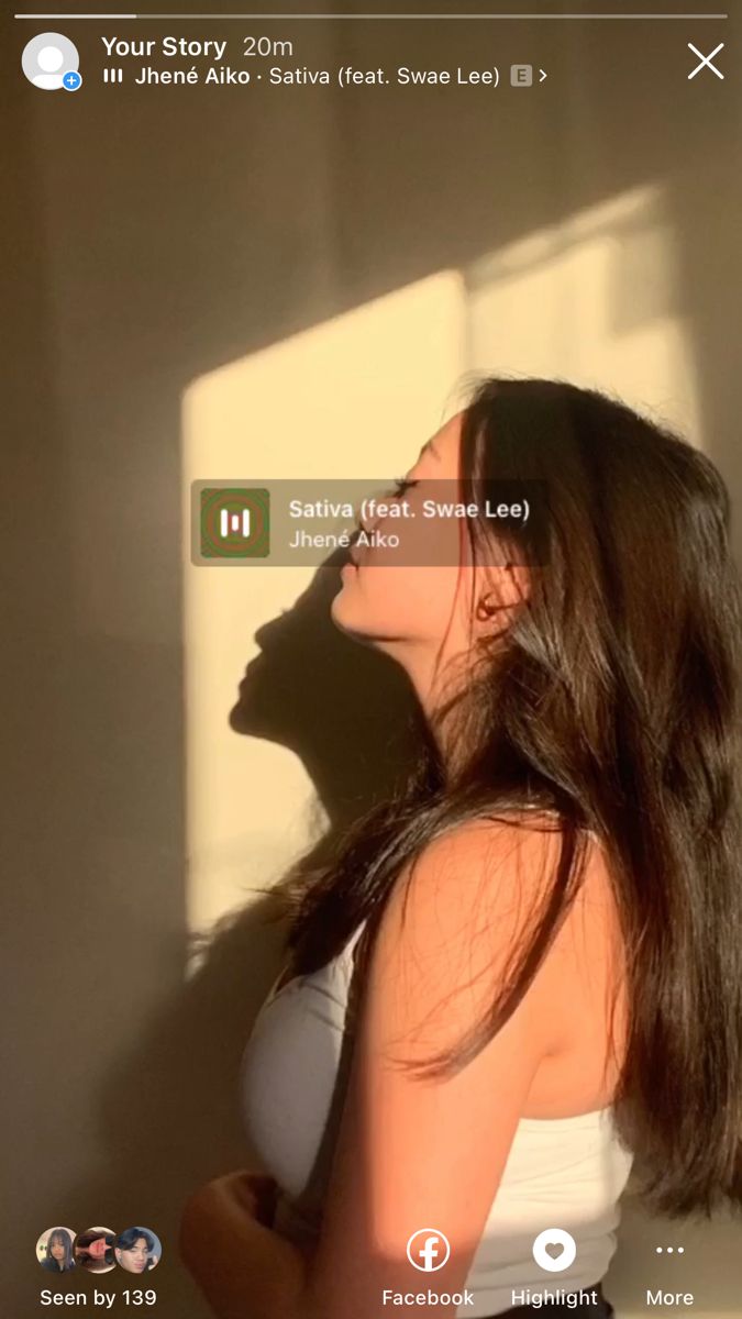 a woman standing in front of a window with her shadow on the wall behind her