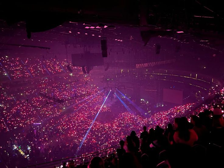 a large group of people at a concert with bright lights on the stage and in the crowd