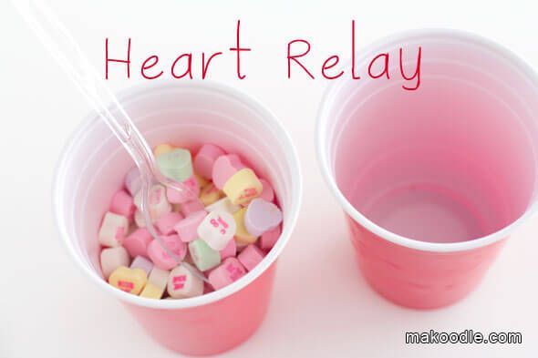 two plastic cups filled with conversation hearts and the words heart relay written in red above them