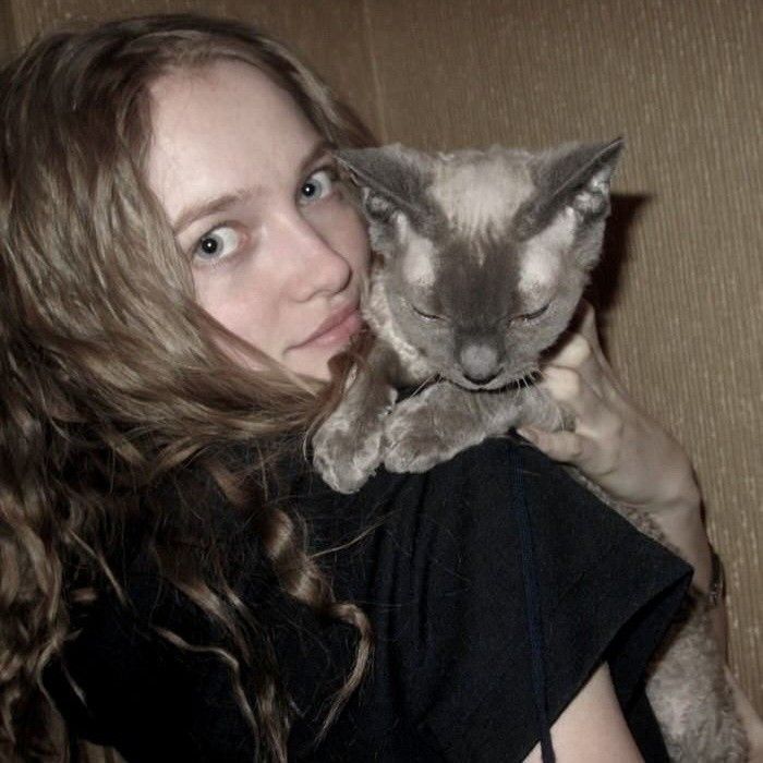 a woman holding a cat in her arms and looking at the camera with an intense look on her face