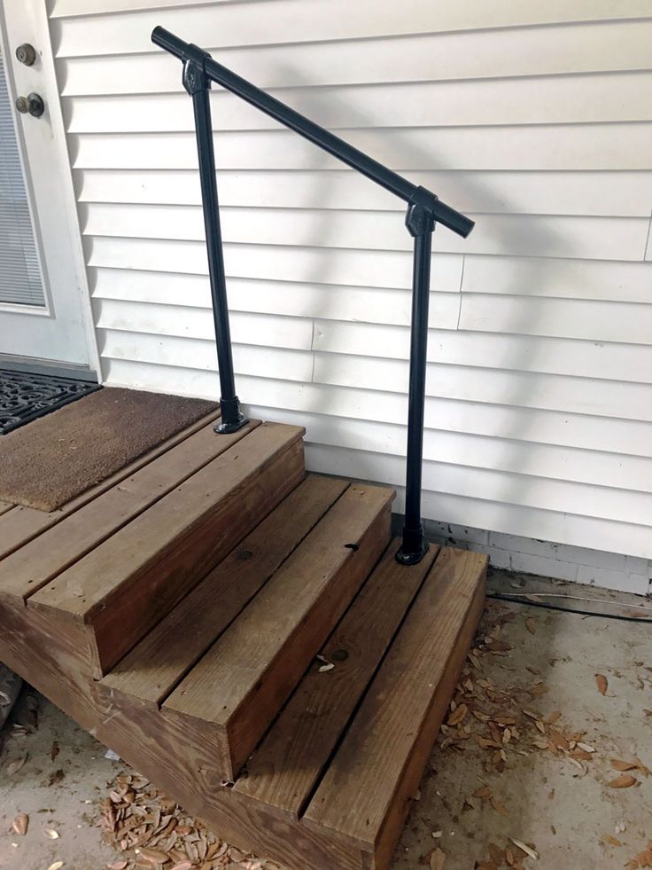 a set of stairs made out of wood and metal handrails on the side of a house