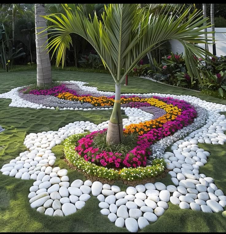 a flower garden with rocks and flowers in the center, surrounded by palm trees on either side