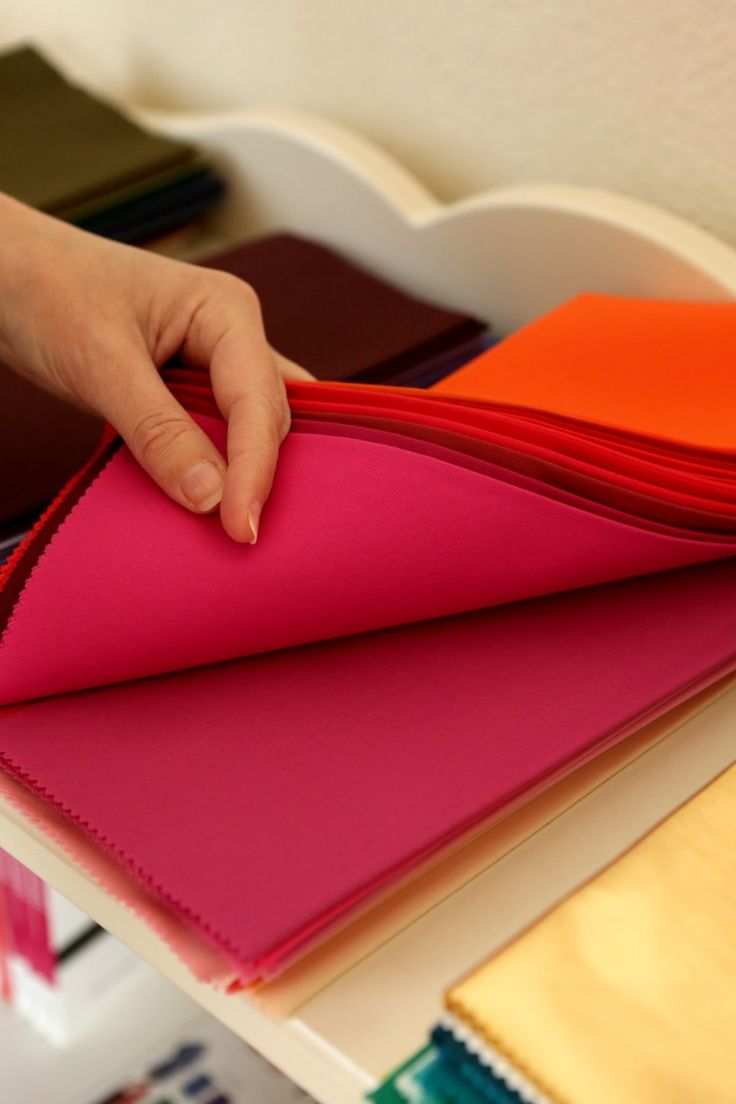 a hand is on top of several different colored papers and folders that are sitting on a table