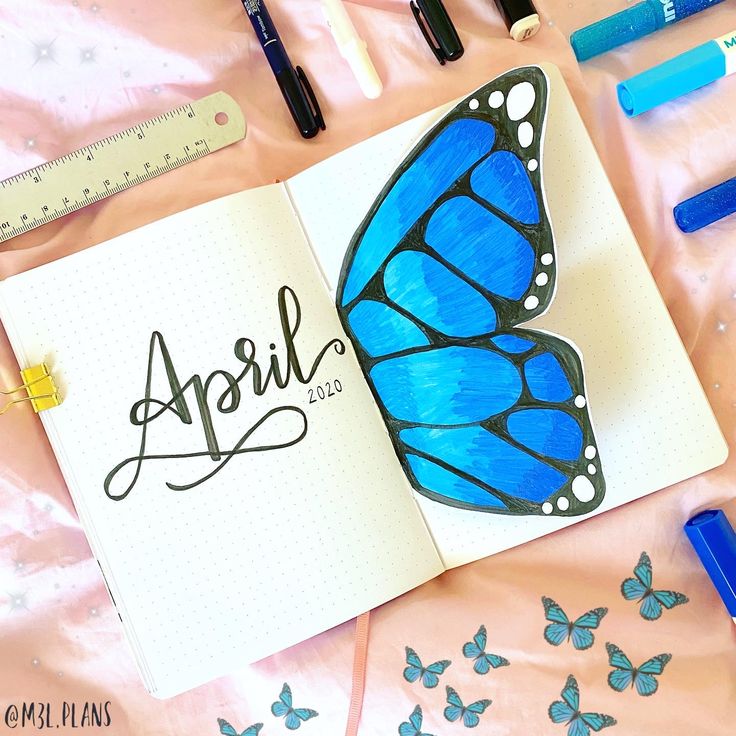 an open notebook with the word april written on it next to some markers and pencils