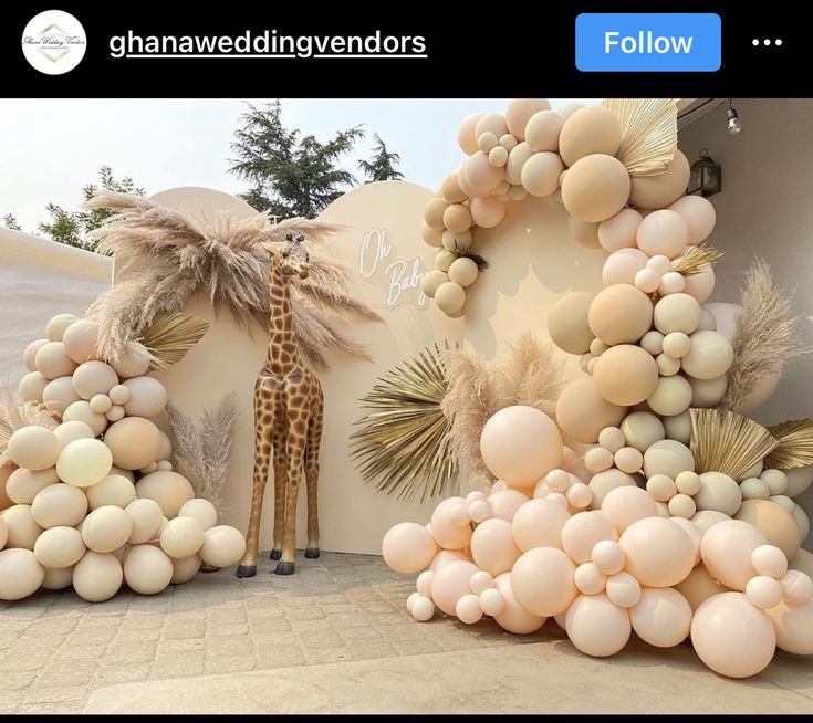 a giraffe is standing next to balloons and palm trees