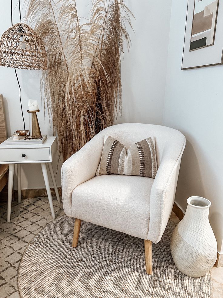 a white chair sitting on top of a rug next to a table with a lamp