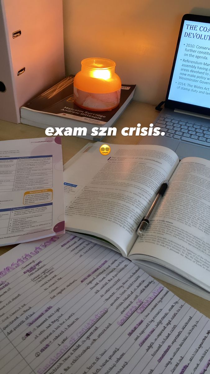 an open book sitting on top of a desk next to a laptop computer and a lit candle