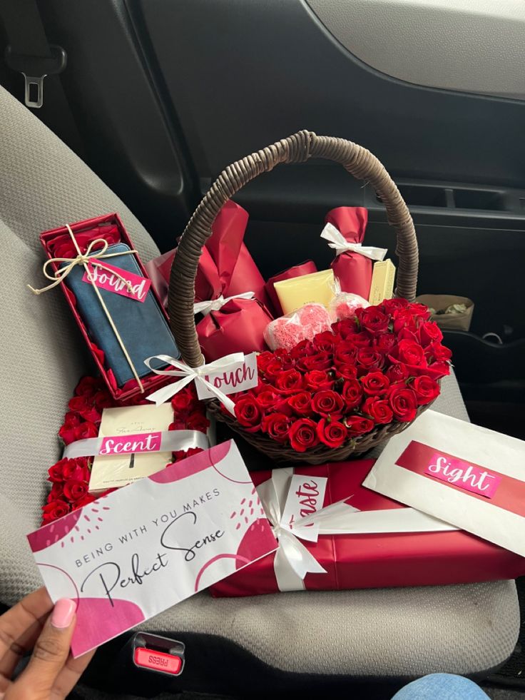 a basket filled with red roses sitting on top of a car seat