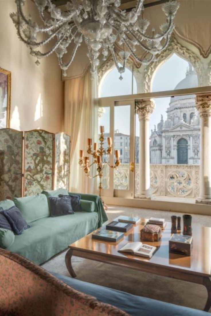 a living room filled with furniture and a chandelier hanging over it's windows