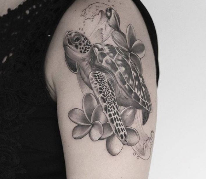 a woman's arm with a turtle and flowers tattoo on it